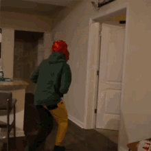 a man in a red hat is standing in a hallway next to a basketball hoop hanging on the wall .