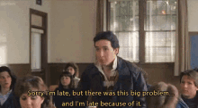 a man in a leather jacket is talking to a group of people in a classroom and says sorry i 'm late