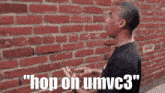 a man standing in front of a brick wall with the words " hop on umvc3 " on the bottom