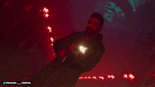 a man in a black jacket is holding a gun with the hashtag pranay_varma below him