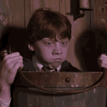a young boy with red hair is holding a bucket in his hands