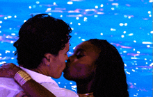 two people kissing in front of a blue background