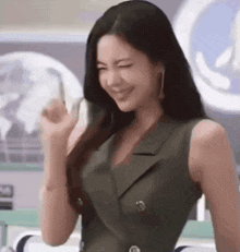 a woman in a green dress is smiling and making a funny face .