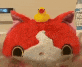 a red stuffed animal with a yellow rubber duck on top of it .