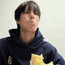 a man wearing a blue hoodie with the letter d on it is eating a piece of cake