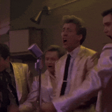 a group of men singing into microphones in a dimly lit room