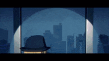 a man in a hat stands in front of a window with a city skyline in the background