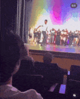 a group of people are sitting in a theater watching a performance on stage .