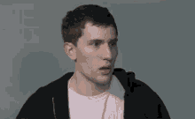 a man wearing a black hoodie and a pink shirt