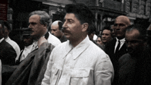 a man in a white shirt is standing in a crowd of people
