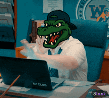 a man wearing a crocodile mask sits at a desk with a laptop that says av club on it