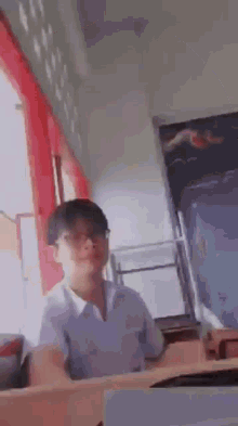a young man wearing glasses and a white shirt is making a funny face in a room .