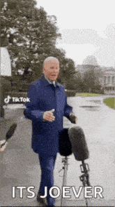 a man in a suit is standing in front of a microphone and a bicycle .