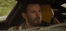 a man is sitting in the driver 's seat of a car with a yellow seat .