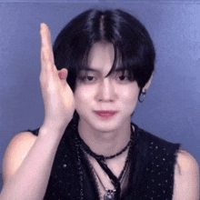 a young man with black hair is making a funny face with his hands .