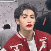 a man wearing a red jacket with the letter t on the front