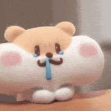 a stuffed animal with a mustache is crying with a blue tear coming out of its nose .