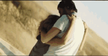 a man and a woman are hugging each other while standing on top of a hill .