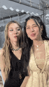 two women standing next to each other one wearing a necklace