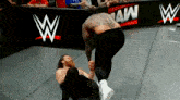 two wrestlers are fighting on a wrestling mat in front of a wwe sign .