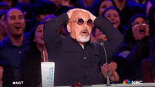 a man wearing sunglasses stands in front of a microphone with his hands in the air
