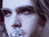 a close up of a person 's face with a glass object in their mouth