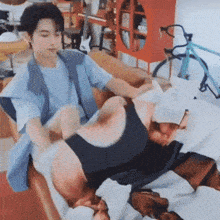 a man is sitting on a couch holding another man 's leg while a bicycle is in the background .