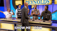 a man in a suit stands in front of a sign that says reynolds