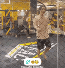 a man is standing in a boxing ring behind a chain link fence .