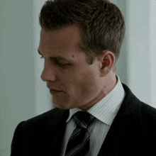 a man in a suit and tie looks down with his eyes closed