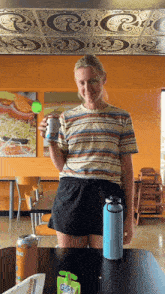 a woman in a striped shirt is holding a can of gatorade