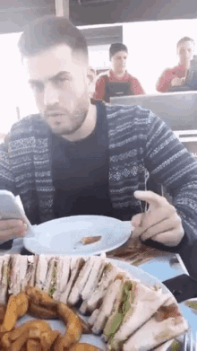a man is sitting at a table with a plate of food and a fork in his hand .