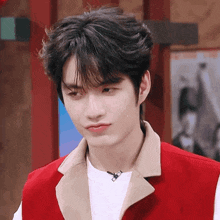 a young man wearing a red vest and a white shirt is making a funny face