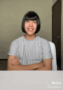 a woman with short hair is sitting at a desk with her arms crossed and a tiktok watermark