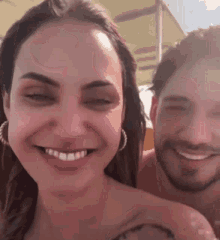 a man and a woman are smiling and looking at the camera .