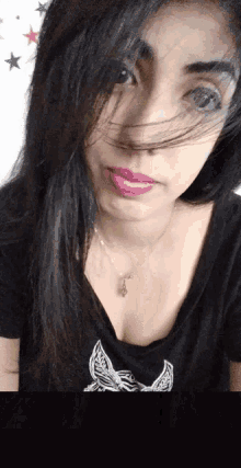 a woman wearing a black shirt with a butterfly on it looks at the camera