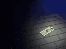 a green and gold motherboard is laying on a black brick floor