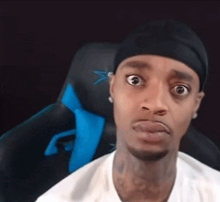 a man wearing a black headband and a white shirt is sitting in a blue chair .