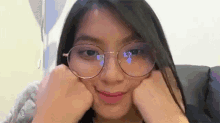 a woman wearing glasses is sitting on a couch and making a face .