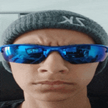 a person wearing a beanie and sunglasses with the letter xs on it
