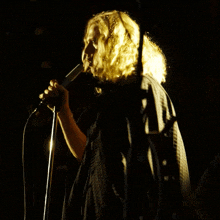 a woman with blonde hair singing into a microphone