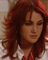 a woman with red hair and a nose ring is wearing a white shirt and a red plaid tie .