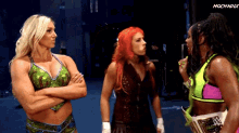 three female wrestlers standing next to each other with their arms crossed .