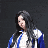 a girl with long black hair is wearing a blue and white jacket .