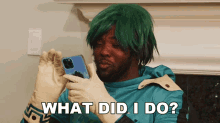 a man in a green wig and gloves is holding a phone and asking what did i do