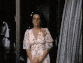 a woman in a floral dress is standing in front of a door .