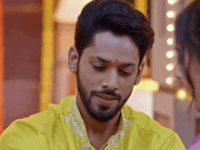 a man with a beard is wearing a yellow shirt .
