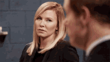 a woman in a black suit looks at a man in a black suit