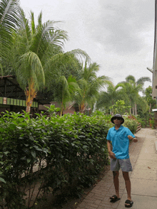 a man wearing a blue shirt and a hat stands in front of a sign that says ' a ' on it