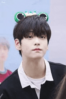 a young man wearing a frog headband is looking at the camera .